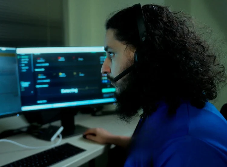Support specialist wearing a headset working at a computer monitor, providing remote technical assistance services