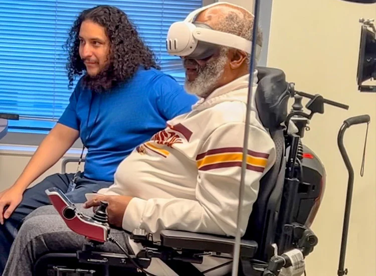 Vista Supports staff assisting an individual with a disability using virtual reality technology while seated in a powered wheelchair