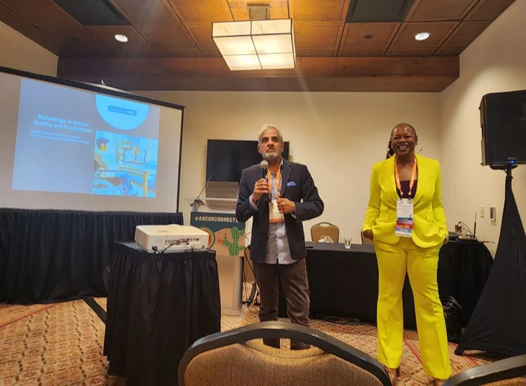 Two presenters speaking at a conference session on assistive technology and productivity, engaging an audience during an educational presentation