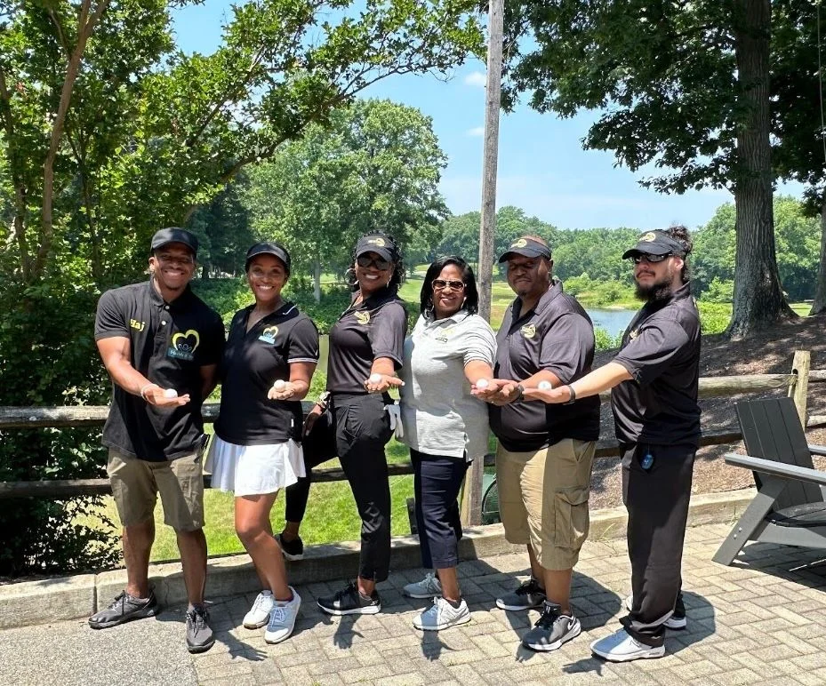 Vista Supports team members standing together outdoors, smiling and extending their hands to represent teamwork, inclusion, and community engagement